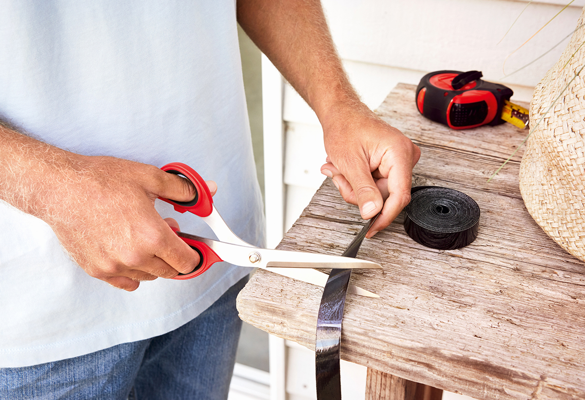 Απεικονίζεται άτομο να κόβει την κολλητική ταινία με ψαλίδι.